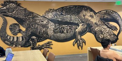 yellow wall with large woodblock image of a salamander intertwined with a lizard.