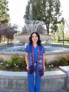 Kaitlin Yang in scrubs and with graduation stole