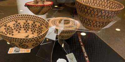 Four intricately woven baskeets from members of the Mono and Yokut Tribes of the Central Valley in a display case.