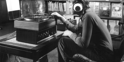 Vintage photo of a student listening to an LP on a record player with headphones in a record store